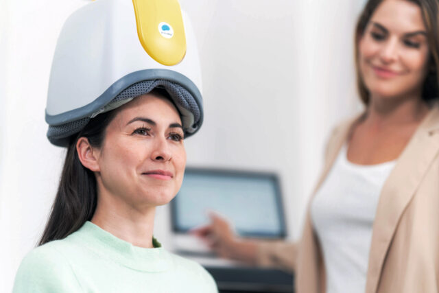 woman seated in TMS machine for therapy