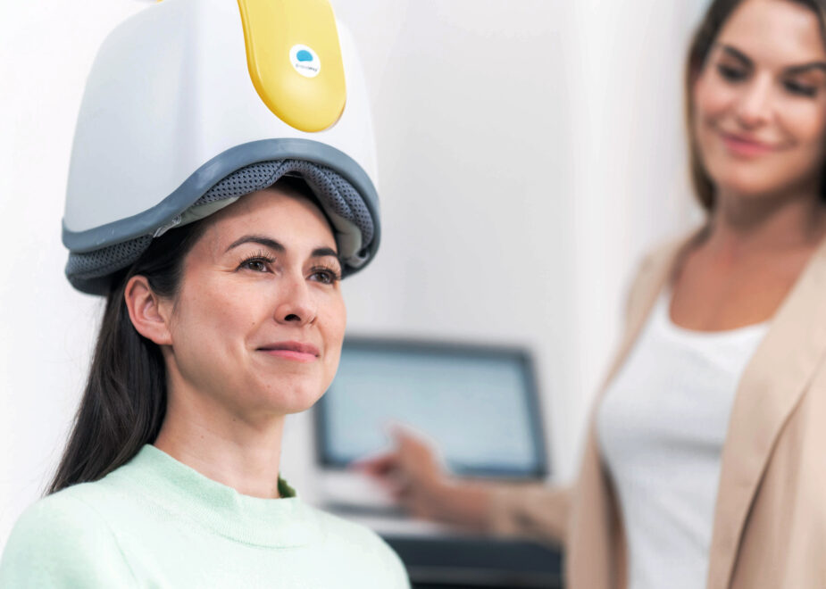 woman seated in TMS machine for therapy